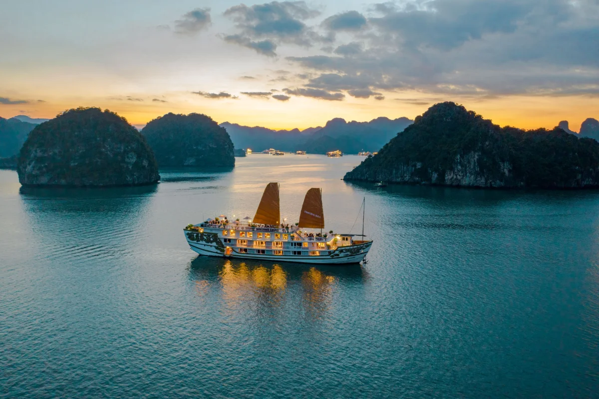 Indochina Sails classic wooden junk in Halong Bay at golden hour