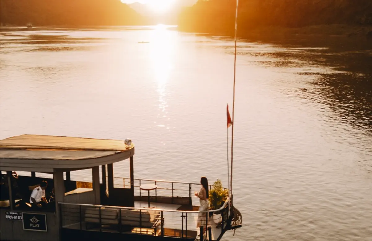 Mekong River at golden hour with wooden longtail boat, serene Indochina landscape