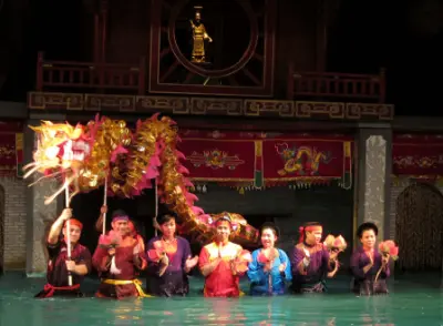 Water puppet master behind bamboo screen with long bamboo poles